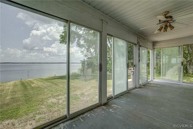 unfurnished sunroom with a wealth of natural light, ceiling fan, and a water view