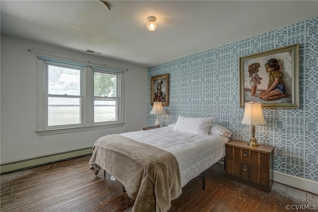 bedroom featuring a baseboard heating unit and hardwood / wood-style floors