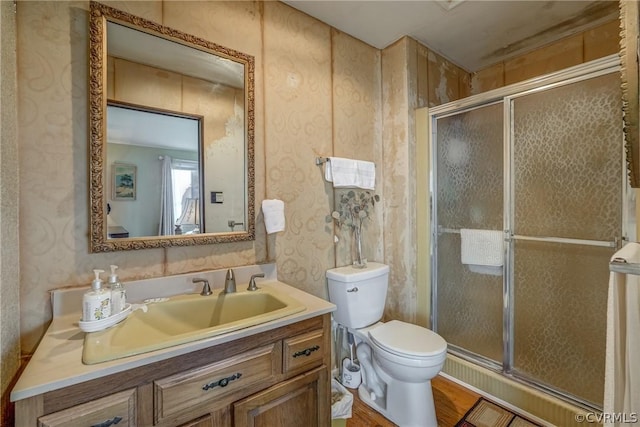 bathroom featuring a shower stall, toilet, vanity, and wood finished floors