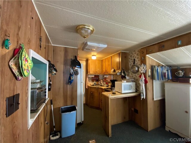 kitchen with a textured ceiling, carpet, and wooden walls