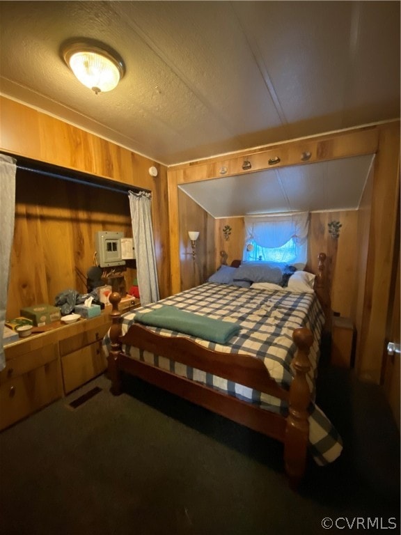 bedroom with wooden walls, carpet floors, and a textured ceiling