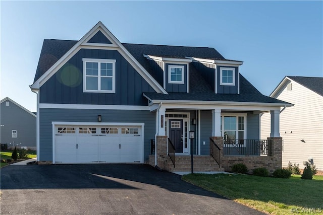 craftsman-style home featuring covered porch, a front yard, and a garage