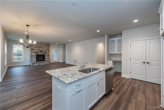 kitchen with sink, white cabinetry, dishwasher, and a fireplace