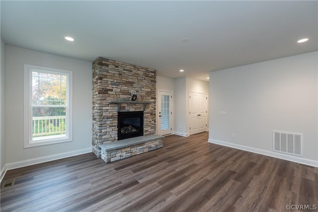 unfurnished living room with dark hardwood / wood-style flooring and a stone fireplace