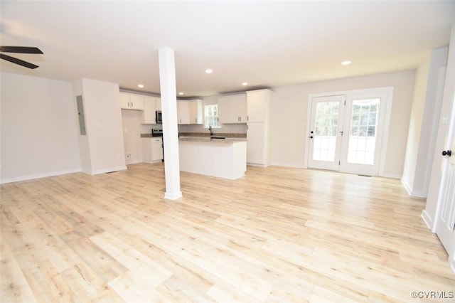 unfurnished living room featuring electric panel, french doors, sink, light hardwood / wood-style flooring, and ceiling fan