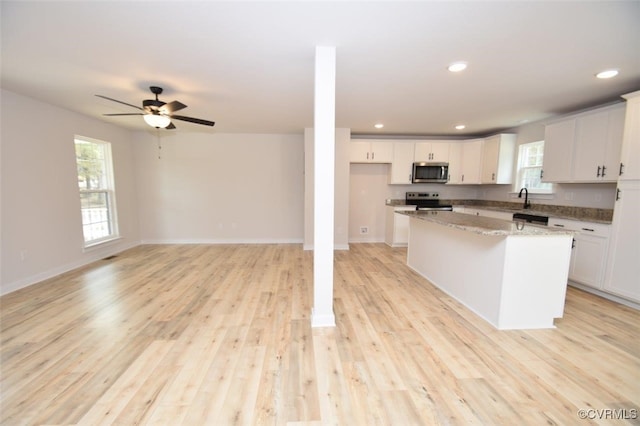 kitchen with white cabinets, a kitchen island, appliances with stainless steel finishes, and light hardwood / wood-style flooring