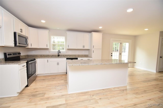 kitchen featuring plenty of natural light, a kitchen island, light hardwood / wood-style floors, and stainless steel appliances