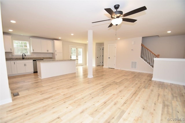 unfurnished living room featuring ceiling fan, light wood-type flooring, and sink