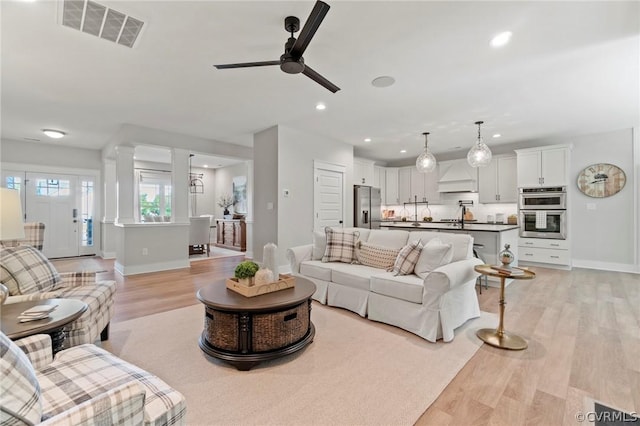 living room featuring ceiling fan, sink, and light wood-type flooring