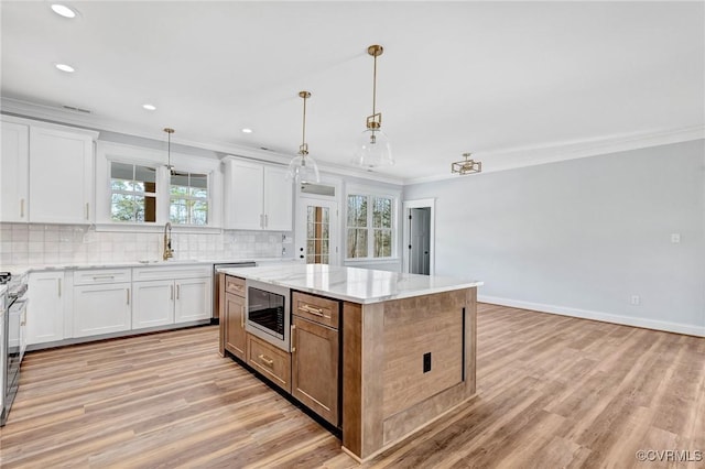 kitchen with light stone countertops, white cabinetry, a center island, a healthy amount of sunlight, and stainless steel appliances