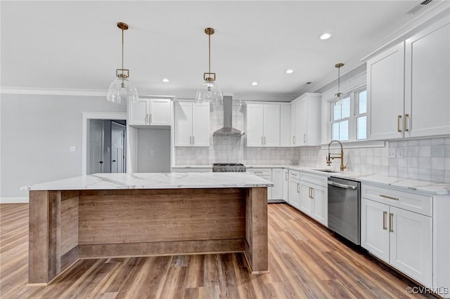 kitchen featuring appliances with stainless steel finishes, wall chimney range hood, white cabinets, a center island, and light hardwood / wood-style floors