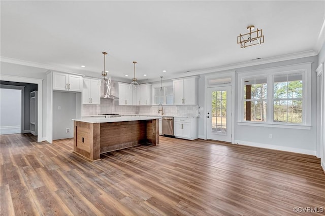 kitchen with white cabinets, wall chimney range hood, hanging light fixtures, stainless steel dishwasher, and a kitchen island