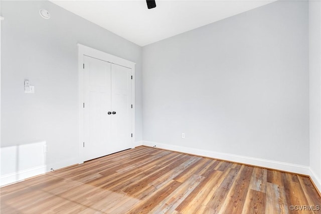 unfurnished bedroom featuring ceiling fan, a closet, and hardwood / wood-style floors