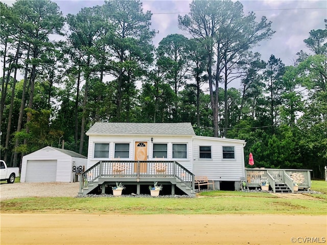 view of front of property featuring a garage, an outdoor structure, a front lawn, and a deck