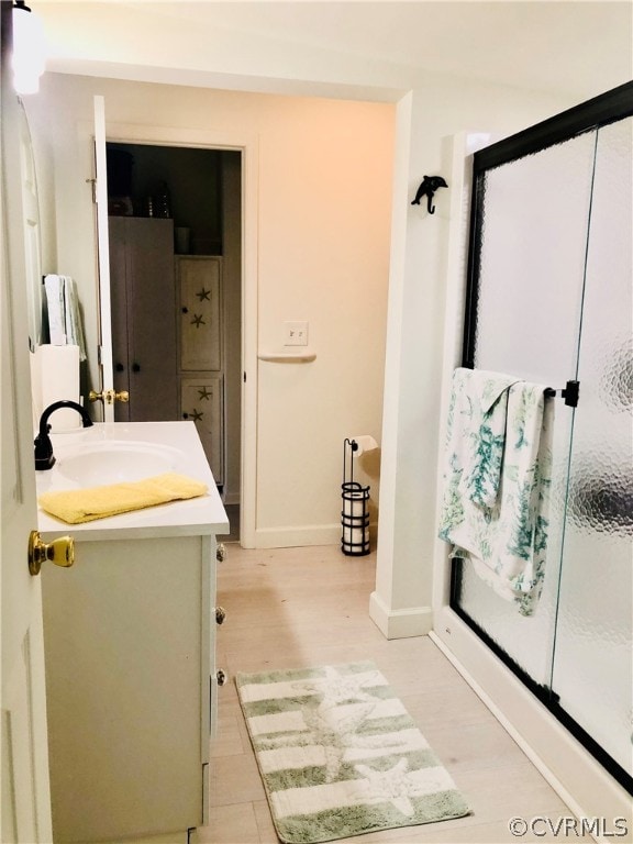 bathroom featuring wood-type flooring, a shower with shower door, and vanity