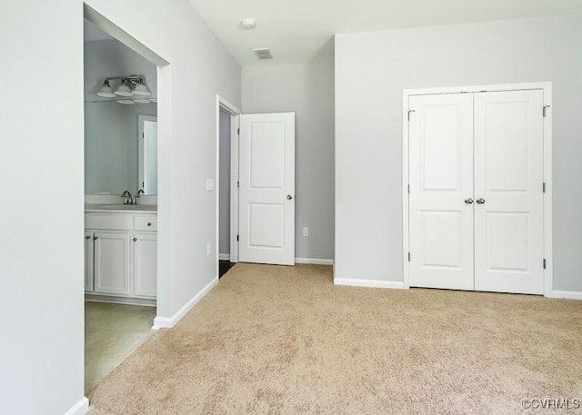 unfurnished bedroom featuring a closet, light colored carpet, and sink