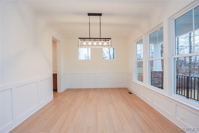 unfurnished dining area with ornamental molding, light hardwood / wood-style floors, and a wealth of natural light