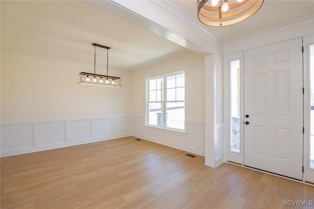 foyer entrance with light hardwood / wood-style flooring and ornamental molding