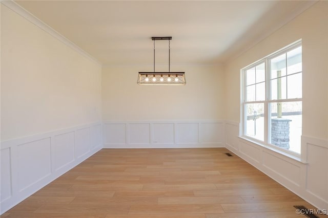 unfurnished dining area with ornamental molding and light hardwood / wood-style floors