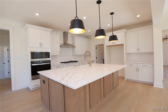 kitchen with white cabinets, oven, a kitchen island with sink, and wall chimney range hood