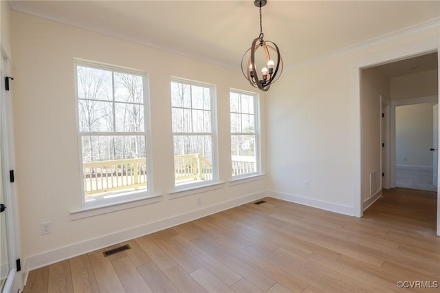 unfurnished dining area with ornamental molding, a healthy amount of sunlight, a notable chandelier, and light wood-type flooring