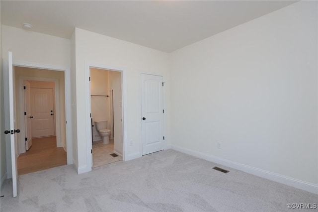 unfurnished bedroom featuring ensuite bathroom and light colored carpet