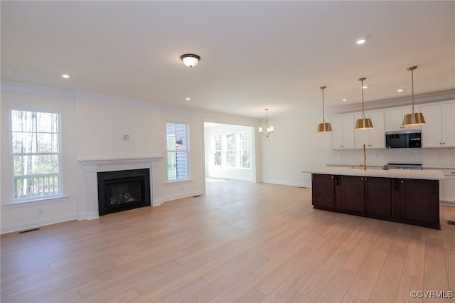 kitchen with white cabinets, hanging light fixtures, sink, and light hardwood / wood-style floors