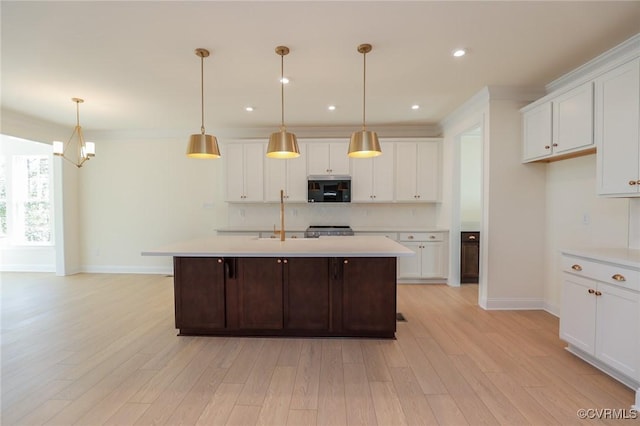 kitchen featuring a center island with sink, light hardwood / wood-style flooring, white cabinets, and decorative light fixtures