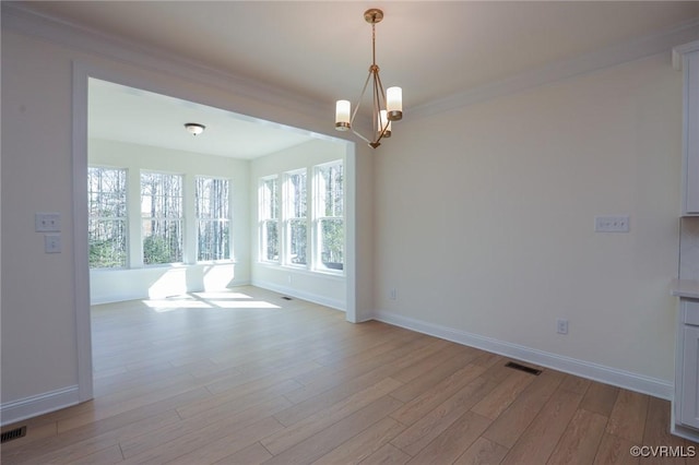 spare room featuring light hardwood / wood-style floors, crown molding, and a notable chandelier