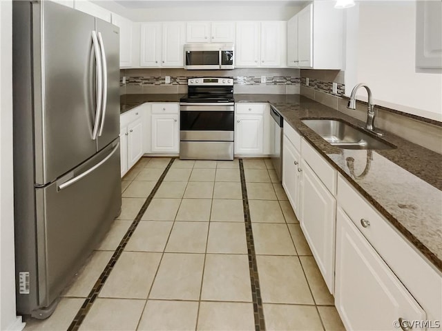 kitchen featuring white cabinets, stainless steel appliances, dark stone counters, and sink