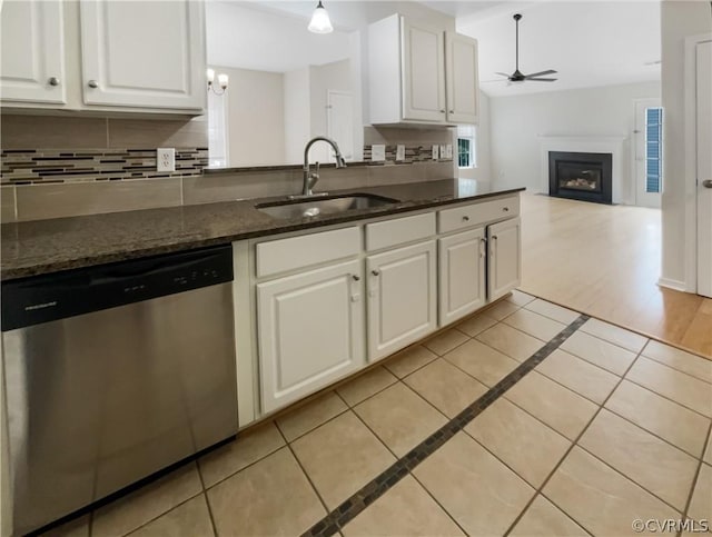 kitchen featuring white cabinets, sink, stainless steel dishwasher, dark stone countertops, and tasteful backsplash