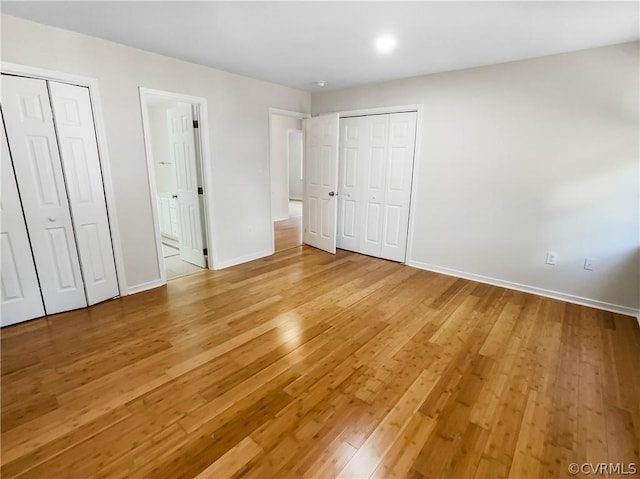 unfurnished bedroom featuring wood-type flooring and multiple closets