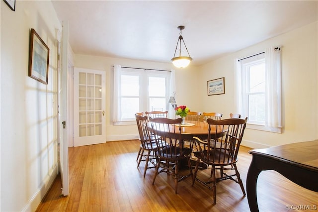 dining room with french doors, a healthy amount of sunlight, and light hardwood / wood-style floors