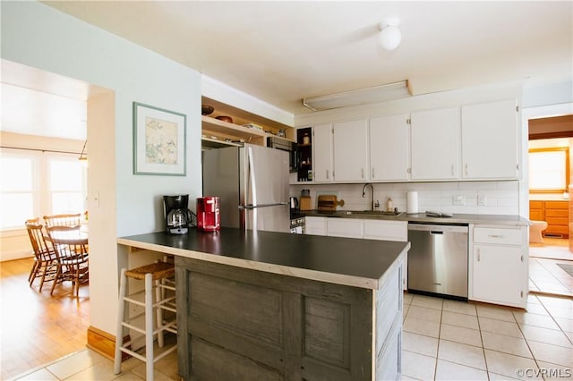 kitchen with white cabinets, light tile patterned floors, plenty of natural light, and appliances with stainless steel finishes