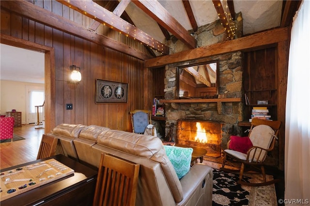 living room with hardwood / wood-style floors, wooden walls, lofted ceiling with beams, and a stone fireplace