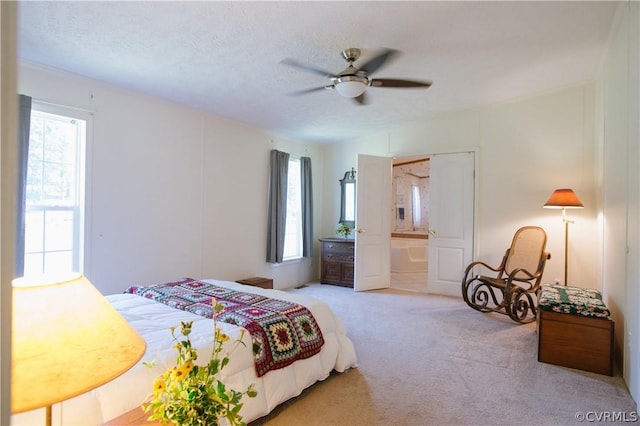 bedroom featuring ceiling fan, ensuite bathroom, light carpet, and a textured ceiling