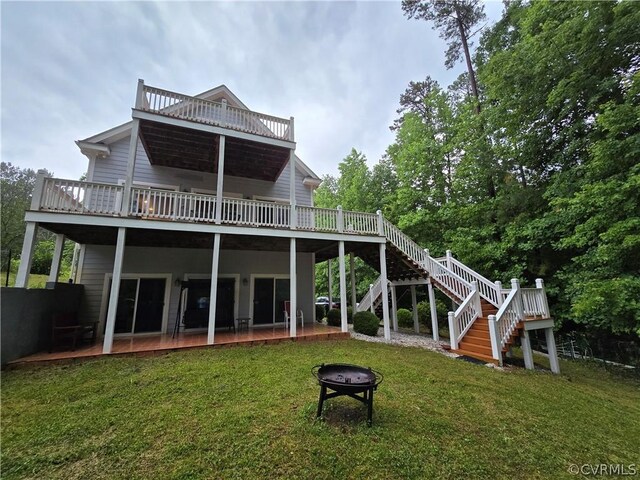 rear view of house featuring an outdoor fire pit, a lawn, and a wooden deck