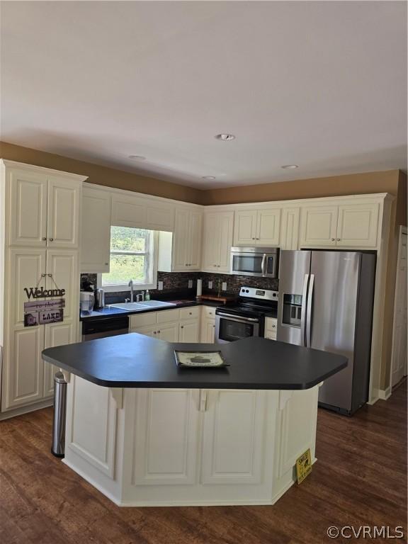 kitchen featuring sink, a breakfast bar, appliances with stainless steel finishes, white cabinets, and dark hardwood / wood-style flooring