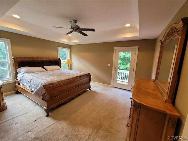 bedroom featuring a tray ceiling, access to outside, light colored carpet, and ceiling fan