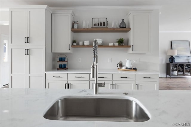 kitchen featuring white cabinets, light stone countertops, and sink