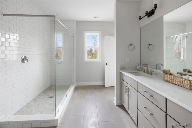 bathroom with tile patterned flooring, vanity, and tiled shower