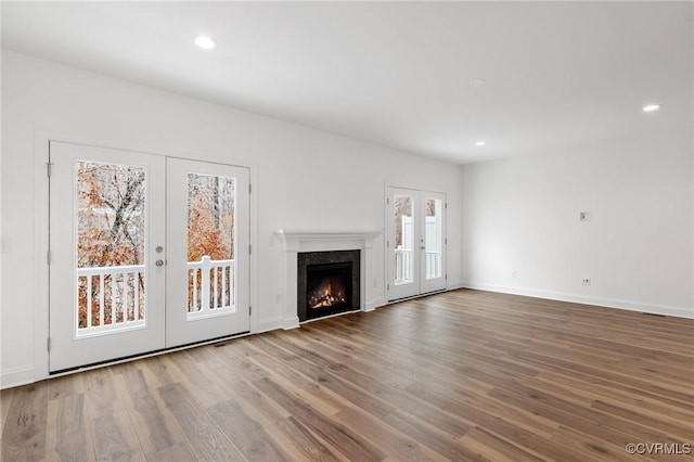 unfurnished living room featuring hardwood / wood-style flooring, a premium fireplace, and french doors