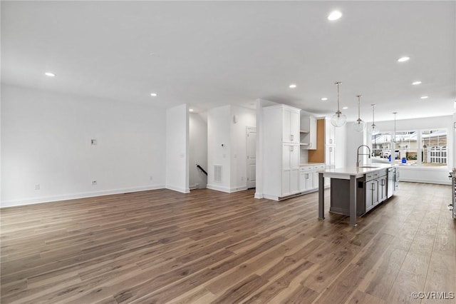 kitchen with sink, decorative light fixtures, white cabinets, an island with sink, and a breakfast bar area