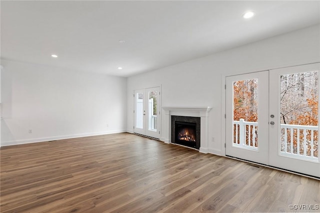 unfurnished living room with a premium fireplace, french doors, and wood-type flooring