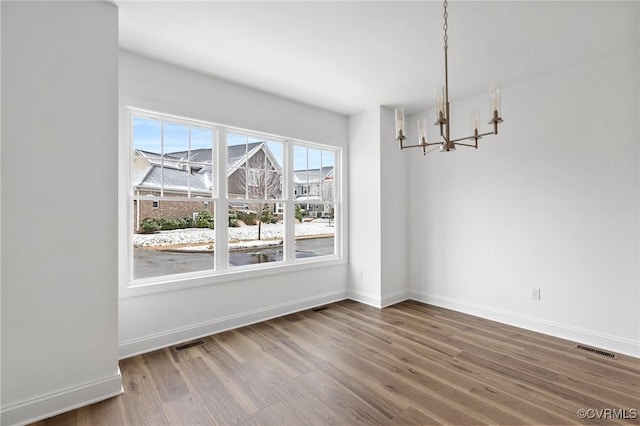 unfurnished dining area featuring hardwood / wood-style flooring and an inviting chandelier