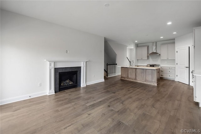 kitchen featuring a center island with sink, dark hardwood / wood-style floors, and wall chimney exhaust hood