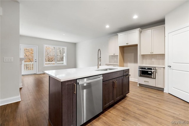 kitchen featuring sink, stainless steel appliances, white cabinets, an island with sink, and dark brown cabinetry