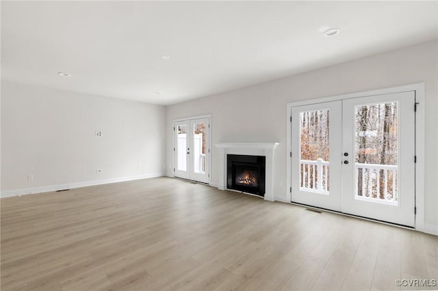 unfurnished living room featuring french doors and light hardwood / wood-style flooring