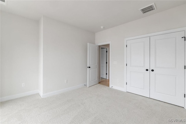 unfurnished bedroom featuring a closet and light colored carpet