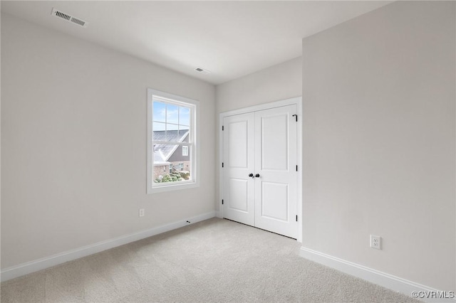 unfurnished bedroom with light carpet and a closet